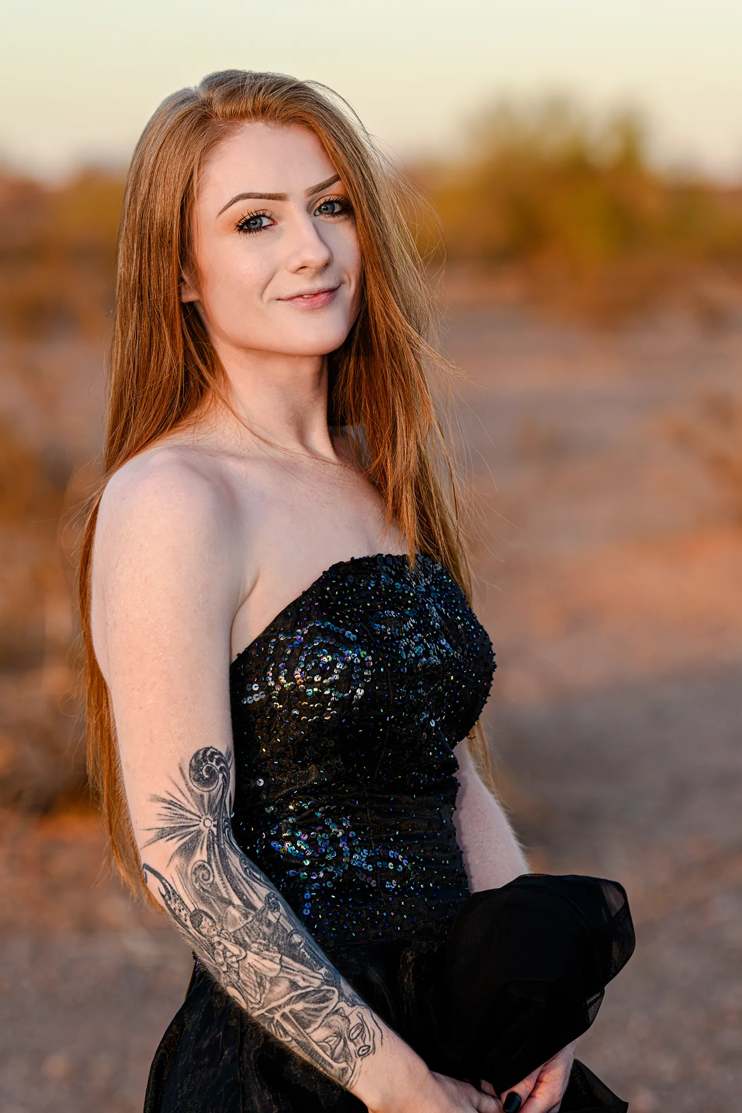 Ashley Brown in a black dress, holding the veil at her waist in the desert light.